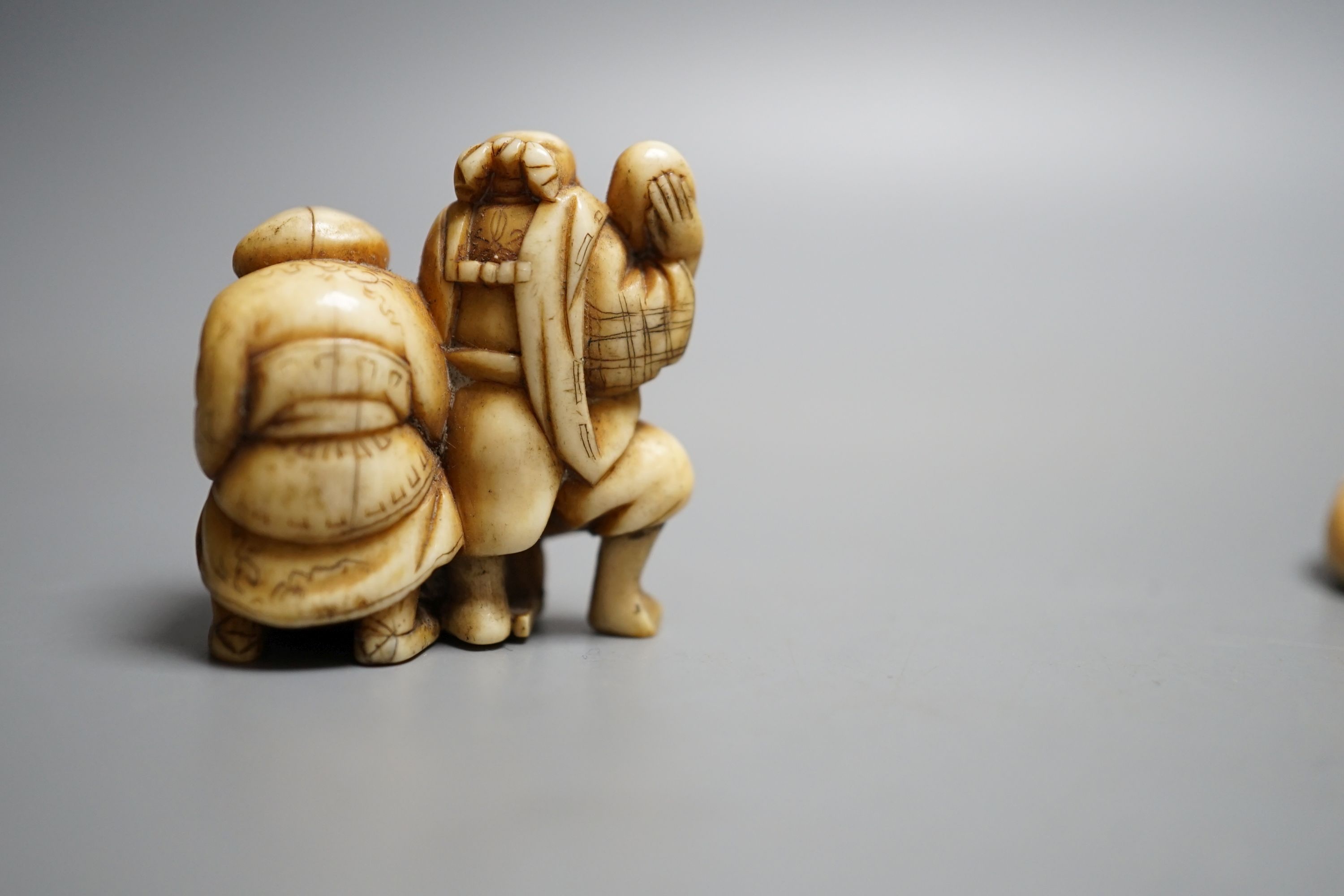 A Japanese Edo period ivory netsuke of Hotei and a Meiji period ivory netsuke of Daikoku and Ebisu, largest 6.5 cms high.
